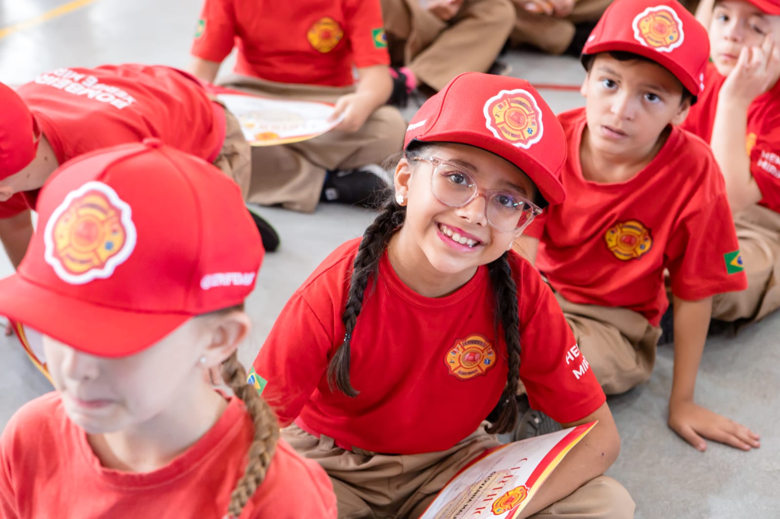 Bombeira mirim sorrindo com o certificado nas mãos
