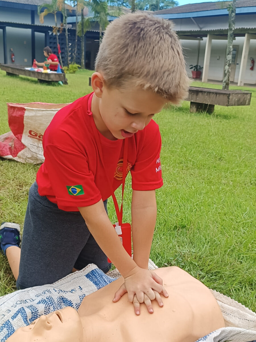 Bombeiro mirim treinando compressões torácicas no manequim de primeiros socorros